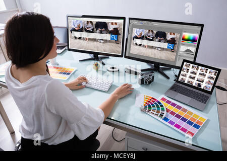 Close-up di una femmina di designer che lavorano su più computer al lavoro Foto Stock