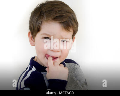 Ritratto di un adorabile ragazzino tre anni che succhia il suo dito, isolati su sfondo bianco Foto Stock