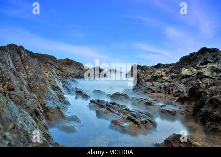 Le onde del mare linea gioco rock di impatto sulla spiaggia Foto Stock