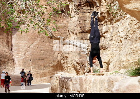 Petra Wadi Musa, Giordania, 9 Marzo 2018: giovane turista praticando un handstand nel Siq della necropoli, molto sportivo in un abito nero Foto Stock