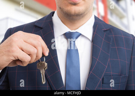 Close-up di agente immobiliare o agente immobiliare tenendo premuto i tasti come sistemazione offerta di alloggiamento concetto su edificio di appartamenti in background Foto Stock