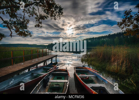 Dock in barca sul lago, albero riflessioni in acqua calma Foto Stock