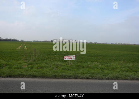 Un bellissimo campo verde con un cartello che diceva "2500 case in questo campo" come la pianificazione è stata concessa per le nuove abitazioni su questo sito, Pagham, West Sussex. Foto Stock