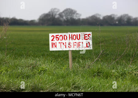 Un bellissimo campo verde con un cartello che diceva "2500 case in questo campo" come la pianificazione è stata concessa per le nuove abitazioni su questo sito, Pagham, West Sussex. Foto Stock