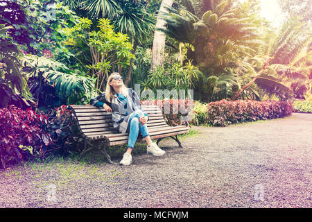 Donna seduta e rilassante sul banco a Botanical Garden park Foto Stock