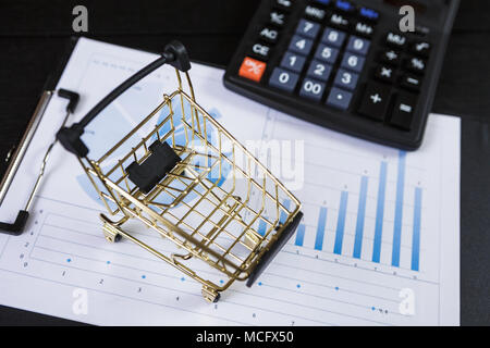 I carrelli della spesa con la calcolatrice sul grafici finanziari Foto Stock