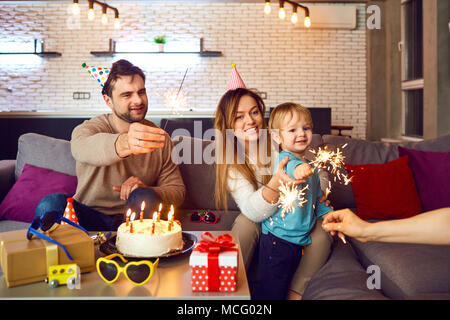 I genitori con una torta con candele congratularmi con il loro bambino per il suo compleanno. Foto Stock