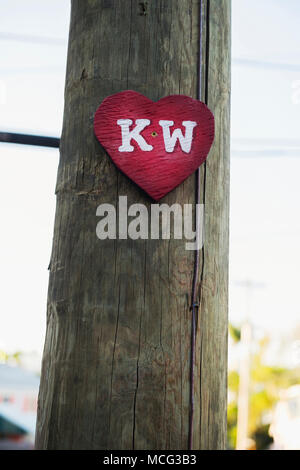 Un rosso cuore di legno segno che simboleggia l'ovest chiave su un palo telefonico di Key West. Foto Stock