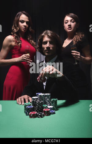 L uomo alla roulette tavolo circondato da belle donne Foto Stock