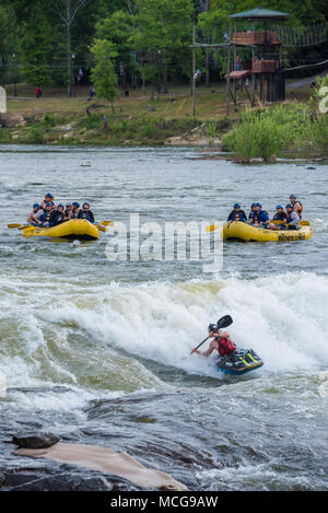 Whitewater rafters e un kayaker godetevi le rapide a paletta a sud mentre zipliners attraversare il fiume Chattahoochee da Columbus, GA per Phenix City, AL. Foto Stock