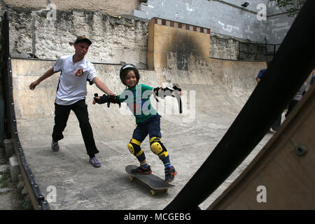 Atene, Grecia. Xv Apr, 2018. Un insegnante di skateboard aiuta un bambino skateboard in un half-pipe ad Atene, in Grecia, il 15 aprile 2018. Come Atene rimane fin dal 2015 una prima porta di chiamata per molti rifugiati che hanno fatto per l'Europa continentale, i giovani rifugiati e migranti sono offerti un opportunità di usare lo skateboard come strumento di emancipazione e di integrazione nella società locale. Credito: Marios Lolos/Xinhua/Alamy Live News Foto Stock