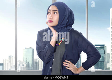 Piuttosto musulmani asiatici donna con le mani sul suo viso oltre i grattacieli sullo sfondo Foto Stock