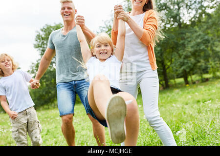 Ragazza romped intorno con genitori e fratello in giardino Foto Stock