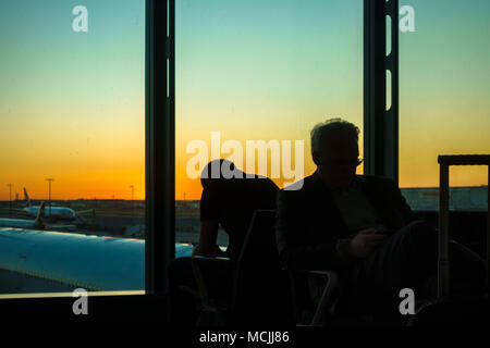 Silhouette di due uomini su airport terminal al crepuscolo, Atene, Grecia Foto Stock