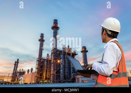 Engineering è utilizzare il notebook e il controllo in piedi nella parte anteriore della raffineria di petrolio per la struttura di un edificio in pesante industria petrolchimica Foto Stock