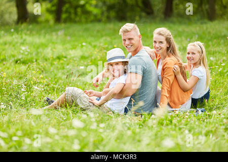 Famiglia con due bambini sono seduti tranquillamente su un prato in estate Foto Stock