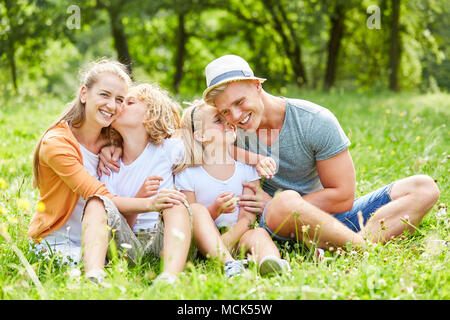 La famiglia felice e due bambini è seduta rilassante nella natura Foto Stock