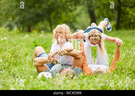 I bambini sono romping con i loro genitori in erba intorno nel giardino in estate Foto Stock