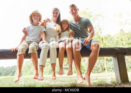 La famiglia felice e i bambini sono seduti rilassati nel parco su una panchina nel parco Foto Stock