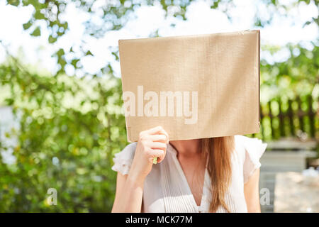 Giovane donna con il suo volto nascosto in una scatola di cartone in estate Foto Stock