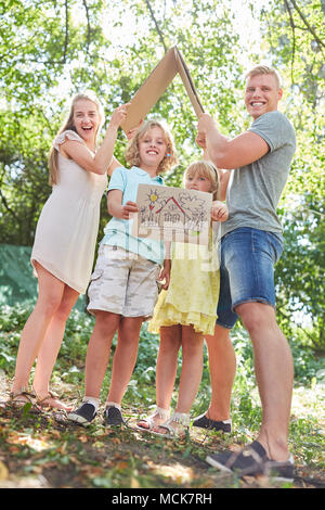 Famiglia è ansioso di possedere una casa e i bambini sono in possesso di un disegno Foto Stock