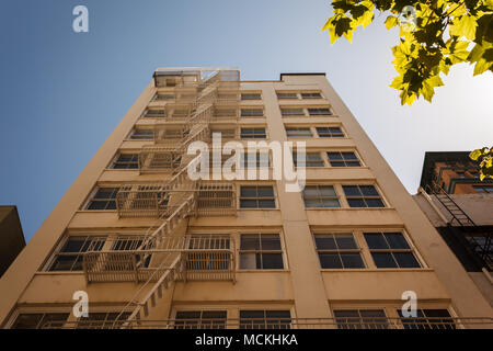 Un uomo con giacca nera e cravatta attraversa la strada a San Francisco, vicino alla funivia di Powell Street, portando con sé una borsa rossa. Foto Stock