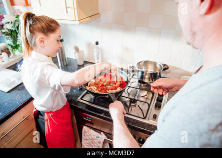 Bambina è imparare a cucinare con suo padre a casa. Essi stanno facendo gli spaghetti alla bolognese insieme. Foto Stock