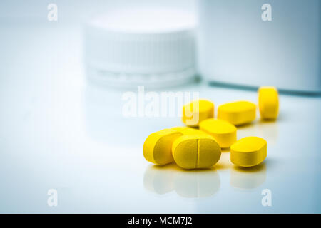 Pila di giallo compresse pillole su sfondo sfocato di pillole di plastica bottiglia con copia spazio. Ibuprofene per il sollievo dei dolori, della cefalea, della febbre alta e anti-i Foto Stock
