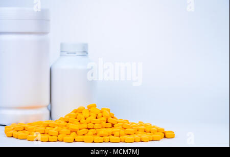 Pila di giallo compresse pillole nei pressi di pillole di plastica bottiglia con etichetta vuota isolata su sfondo bianco con copia spazio. Ibuprofene per il sollievo del dolore, heada Foto Stock
