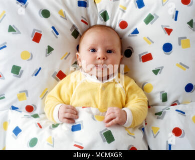 Bambino di sei mesi nel letto con piumone colorato Foto Stock