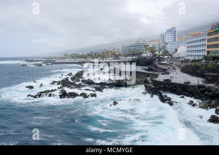 Puerto de la Cruz Tenerife Isole Canarie; mare mosso sul ben mantenuto lungomare come il vento preleva da una tempesta di avvicinamento. Foto Stock