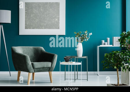 Poltrona verde contro la parete blu con verniciatura in argento in salotto interno con piante Foto Stock