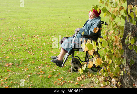 90 anno vecchia donna in carrozzella godendo il sole nel parco pubblico. In Inghilterra. Regno Unito Foto Stock