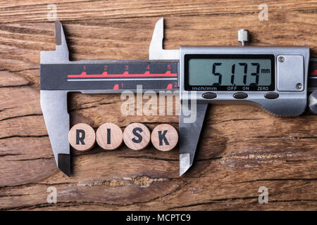 Vista in elevazione di elettronica digitale del calibro a corsoio e blocchi con rischio testo su sfondo di legno Foto Stock