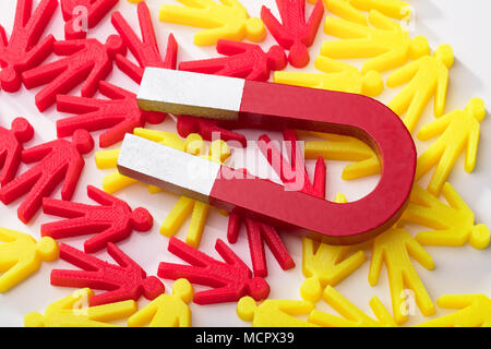 Close-up del magnete a ferro di cavallo con il rosso e il giallo figure umane su sfondo bianco Foto Stock