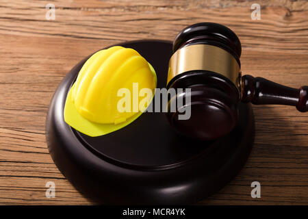 Angolo di Alta Vista di Casco giallo e martello sulla scrivania in legno Foto Stock