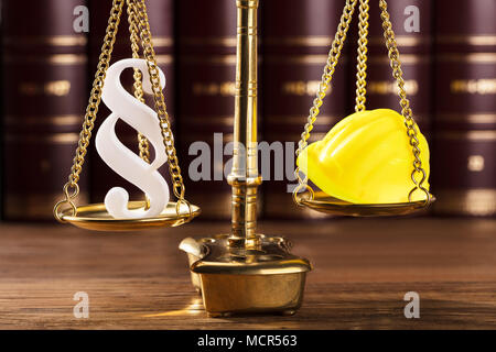 Close-up di punto in bianco simbolo e Casco giallo su scala di giustizia Foto Stock