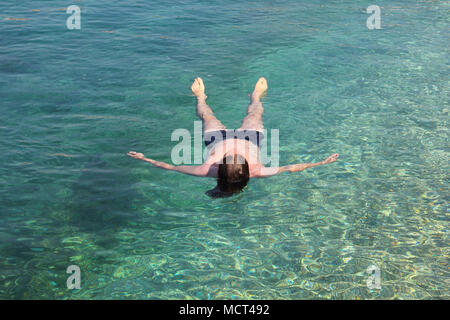 Vacanza e relax concetto, uomo floating rilassata sul retro in trasparente blu pura acqua di mare Foto Stock