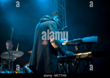 Musicista maschio suona uno strumento musicale sul palco. Artista giocando sulla tastiera synth tasti di pianoforte. Concerto di musica elettronica presso vicina Foto Stock