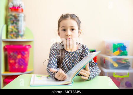 Carino bambina facendo i compiti, la lettura di un libro, pagine da colorare, Scrittura e pittura. I bambini la vernice. Bambini disegnare. Preschooler con libri a casa. I bambini in età prescolare imparare a leggere e a scrivere. Bimbi creativi Foto Stock