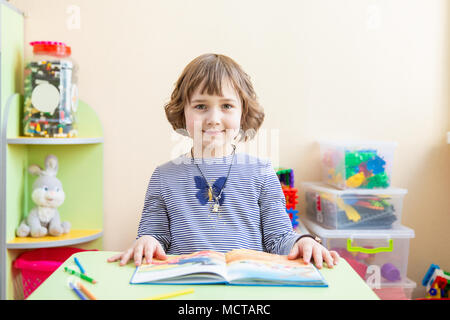 Carino bambina facendo i compiti, la lettura di un libro, pagine da colorare, Scrittura e pittura. I bambini la vernice. Bambini disegnare. Preschooler con libri a casa. I bambini in età prescolare imparare a leggere e a scrivere. Bimbi creativi Foto Stock