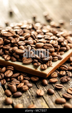 Caffè torrefatto in grani sul vecchio tavolo in legno. Foto Stock