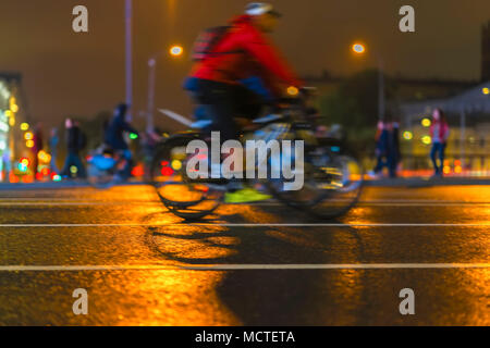 Giovane biker equitazione Bicicletta durante la notte su una strada di città, scena urbana. Abstract sfocata sullo sfondo dello sport Foto Stock