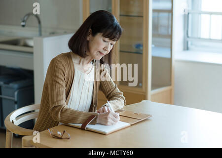 Senior donna scrivere note finale Foto Stock