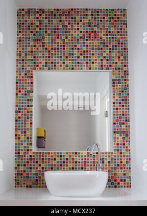 Bagno con lavabo in vetro colorato di piastrelle a mosaico e specchio inset in piastrelle Foto Stock