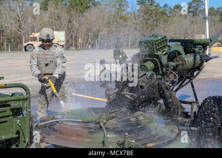 Fort Stewart, Ga., 4 marzo 2018 - Spc. McBride cristiano, artilleryman, Alfa batteria, 1° Battaglione, 118a Campo artiglieria, Springfield, Ga., lambisce la piastra di base della sua M119A3 Obice dopo il completamento di un live-fire qualificazione trapano durante il fine settimana. Il gruppo si sta preparando per la formazione presso il Comune di Readiness Training Center entro la fine di quest'anno. Foto Stock