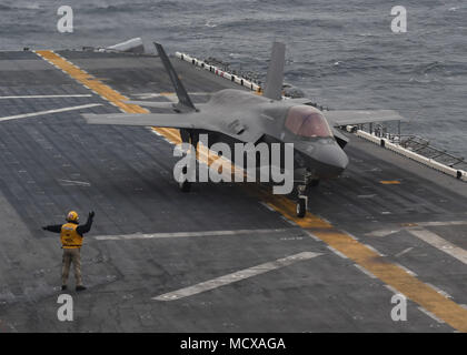 180305-N-GV784-151 Mar Cinese orientale (5 marzo 2018) Capo di aviazione di Boatswain Mate (manipolazione) John Jacob dirige un F-35B II di alleggerimento con Marine Fighter Attack Squadron (VMFA) 121 sul ponte di volo dell'assalto anfibio nave USS Wasp (LHD 1), segnando la prima volta che l'aeromobile ha distribuito a bordo di una U.S. Nave della marina americana e con un Marine Expeditionary Unit nell'Indo-Pacifico regione. (U.S. Foto di Marina di Massa lo specialista di comunicazione 1a classe Alexandra Seeley/rilasciato) Foto Stock