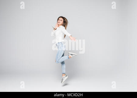 A piena lunghezza Ritratto di una giovane bella bruna ragazza jumping e sorridente felicemente isolato su sfondo bianco Foto Stock