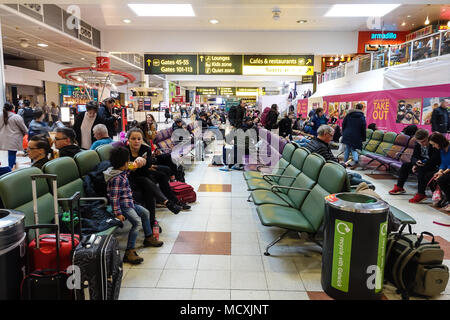 Persone sedersi e aspettare nella sala partenze a Gawtick terminale nord dell'aeroporto per i loro voli per essere assegnato cancelli. Foto Stock