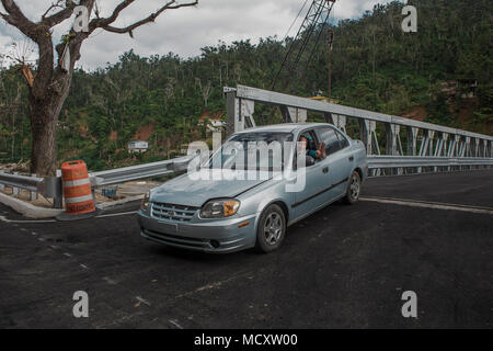 Utuado, Puerto Rico, Marzo 13, 2018--un felice residente del Río Abajo saluta dopo aver attraversato il nuovo ponte costruito nella sua comunità. Dopo l uragano María tore attraverso l'isola, la heavy rain è crollato il ponte precedente lasciando più di 25 famiglie isolate. Oggi, grazie agli sforzi degli enti locali, statali e federali, la Comunità dispone di un nuovo ponte. Foto Stock